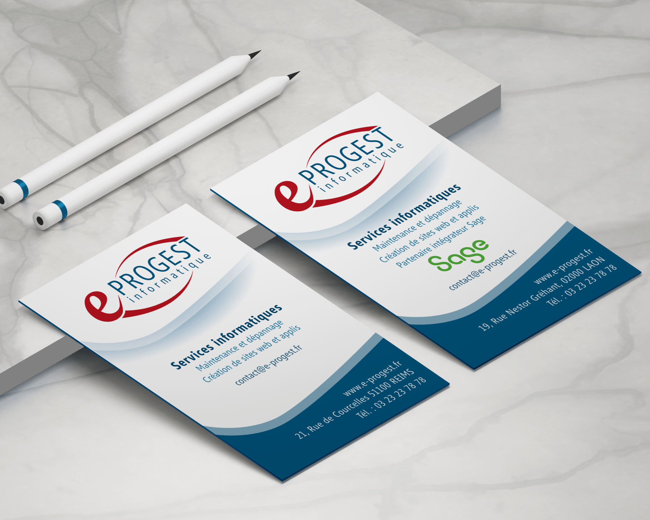 Stack of white business cards featuring the 'PROGEST informatique' logo on a marble surface, with two pencils nearby.